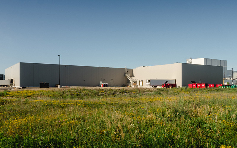 Exterior view of Frulact building, showing shipping docks, large transport truck trailer and large red metal square bins