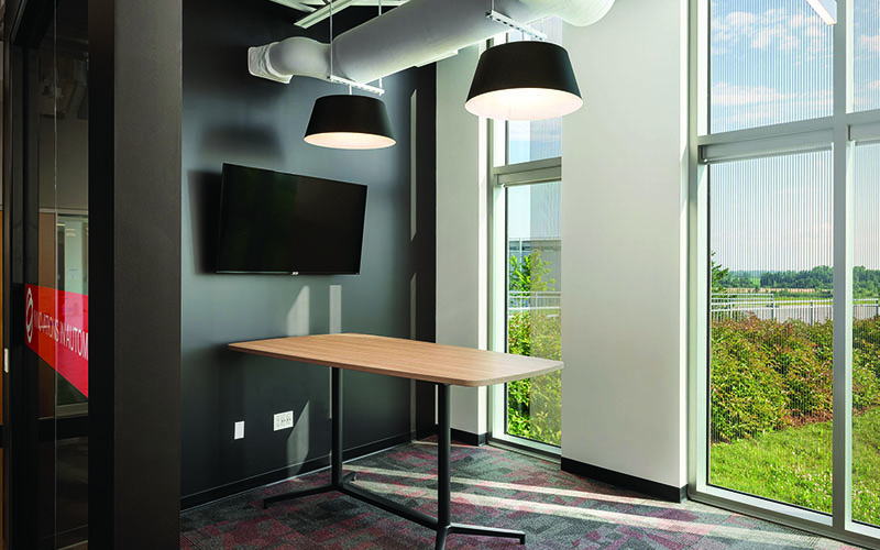BOS Innovations at The Collider Western University Research Park, Photo of an interior office, black wall with TV hanging in the middle, board room table jutting straight out from the wall into the room and an adjacent wall with two floor to ceiling windows placed into the wall