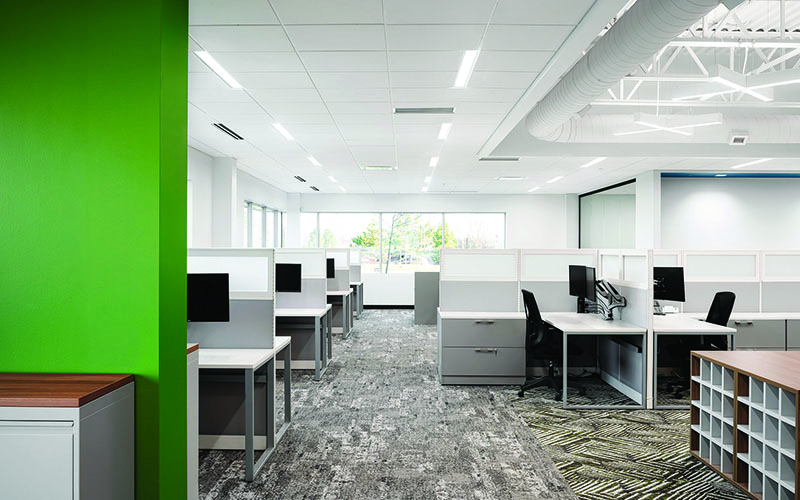 Interior Photo of Spark Power Office, Open office concept, lots of cubicles, Big Glass Window in the distance directly in the center of the photo, and multicolored grey and yellow carpet.