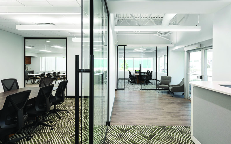 Interior Photo of Spark Power Office, Long hallway to the right side, and down the left is glass walls for a boardroom. hardwood flooring and multicolored grey and yellow carpet.