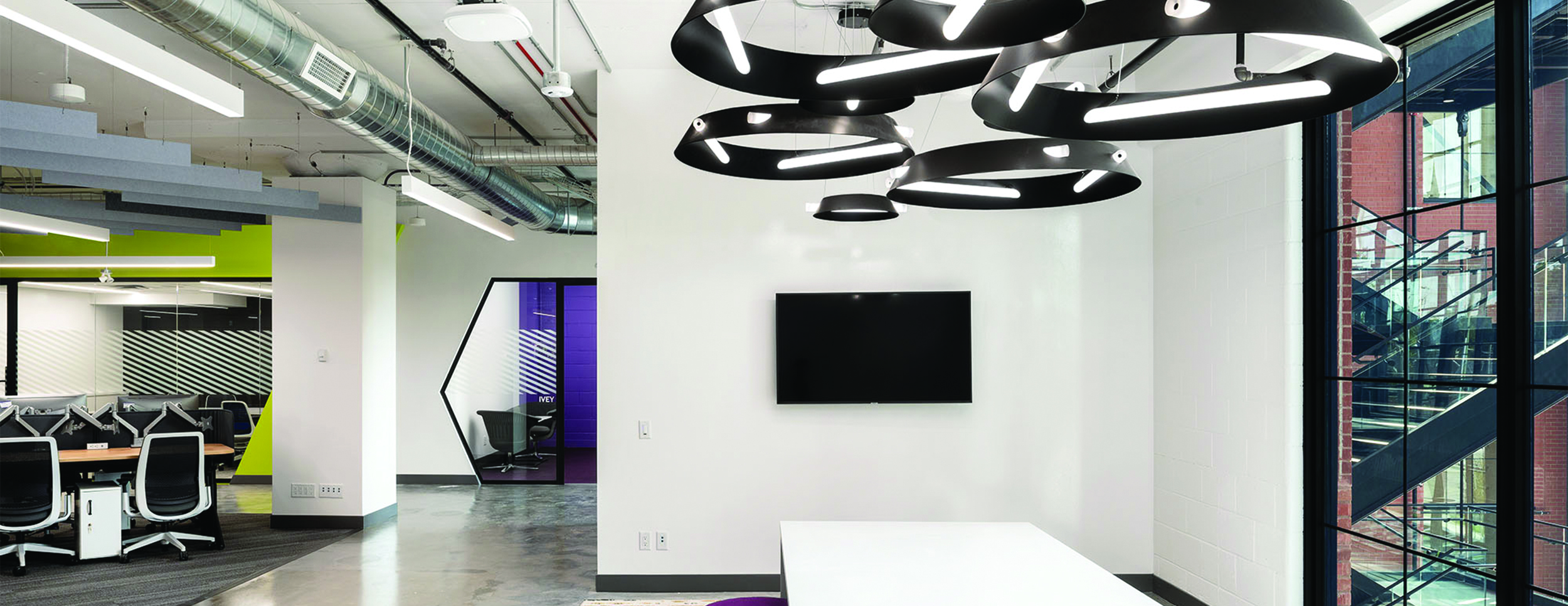 Carfax, interior photo of their office, showing desk space to the left and windows on the right. Open concept with white walls and grey concrete flooring.