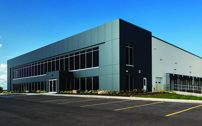 Cole Munro, St. Thomas, Fish processing facility, large industrial building that has windows along the front with dark grey building tiles around it and the rest of the building is white with parking spots out front.