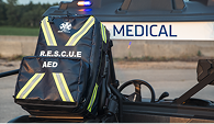 A black Mosaic Medical backpack sitting on the back of a Mosaic Medical golf cart.