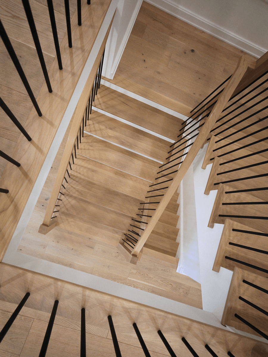 Modern switchback staircase with wooden steps and vertical iron spindles